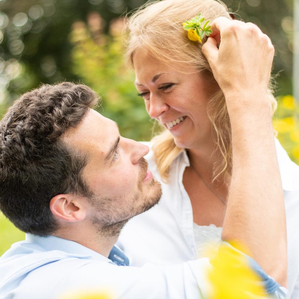 Paar lacht sich an, Blume im Haar